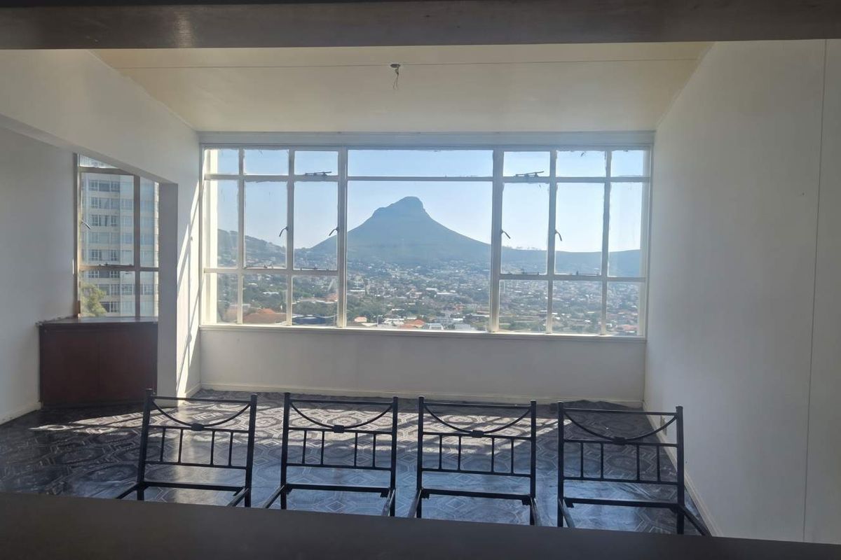 An empty living area featuring large windows that frame a prominent mountain view, offering a blank canvas for renovation and interior design.