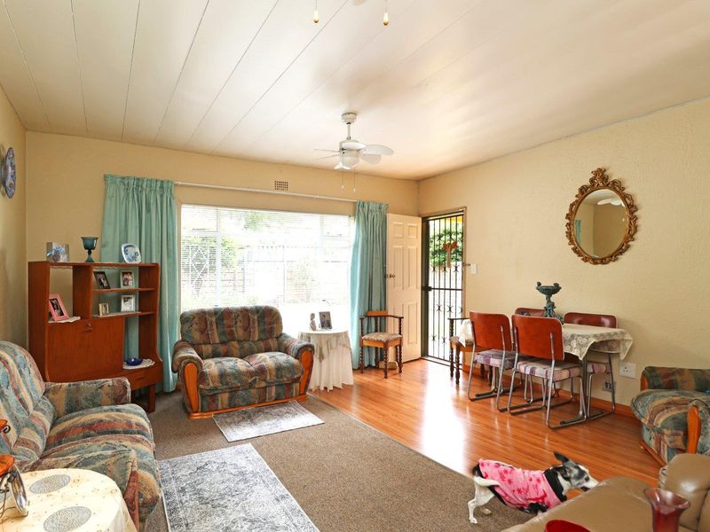 Open plan living and dining area featuring laminate flooring, a ceiling fan, and large windows providing natural light.