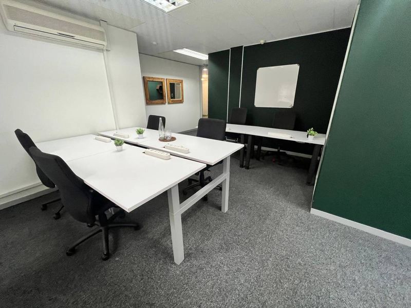 A functional office space featuring carpeted flooring, recessed lighting, a split-system air conditioner, and a dark green accent wall.