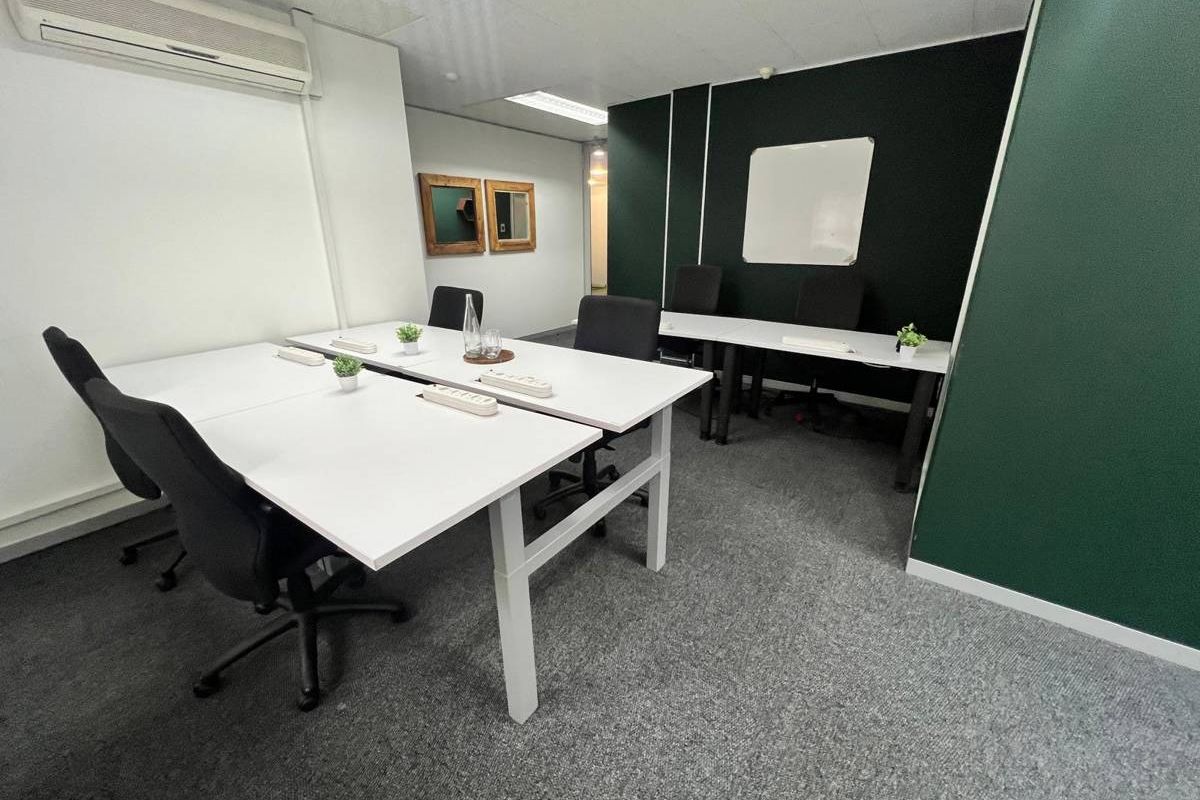 A functional office space featuring carpeted flooring, recessed lighting, a split-system air conditioner, and a dark green accent wall.