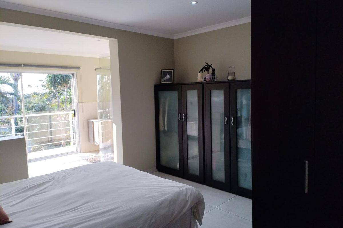 Spacious bedroom featuring built-in cupboards, tiled flooring, and direct access to a private balcony through sliding glass doors.