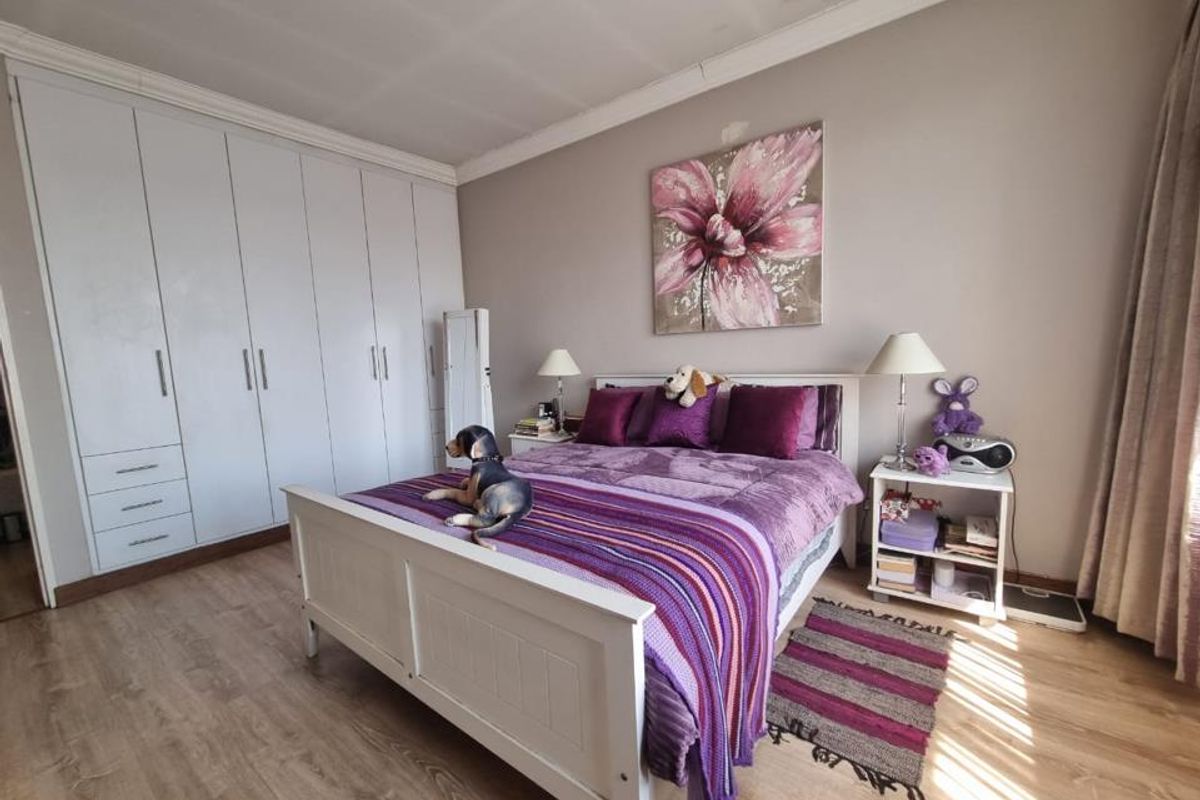 A well-lit bedroom featuring light wood-look flooring, neutral wall tones, and extensive floor-to-ceiling built-in cabinetry for ample storage.