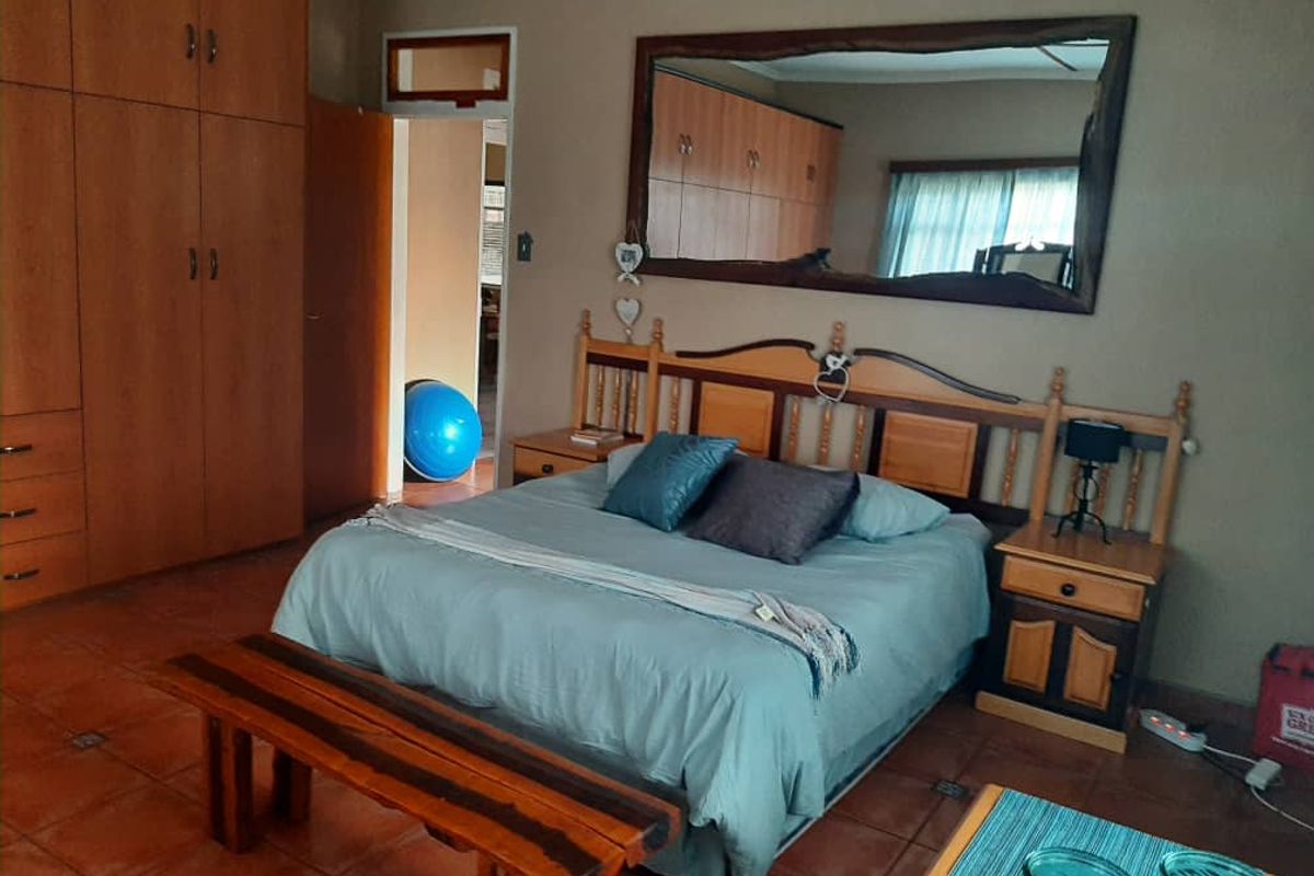 A spacious bedroom featuring built-in wooden cupboards and tiled flooring, offering a functional layout with ample storage space.