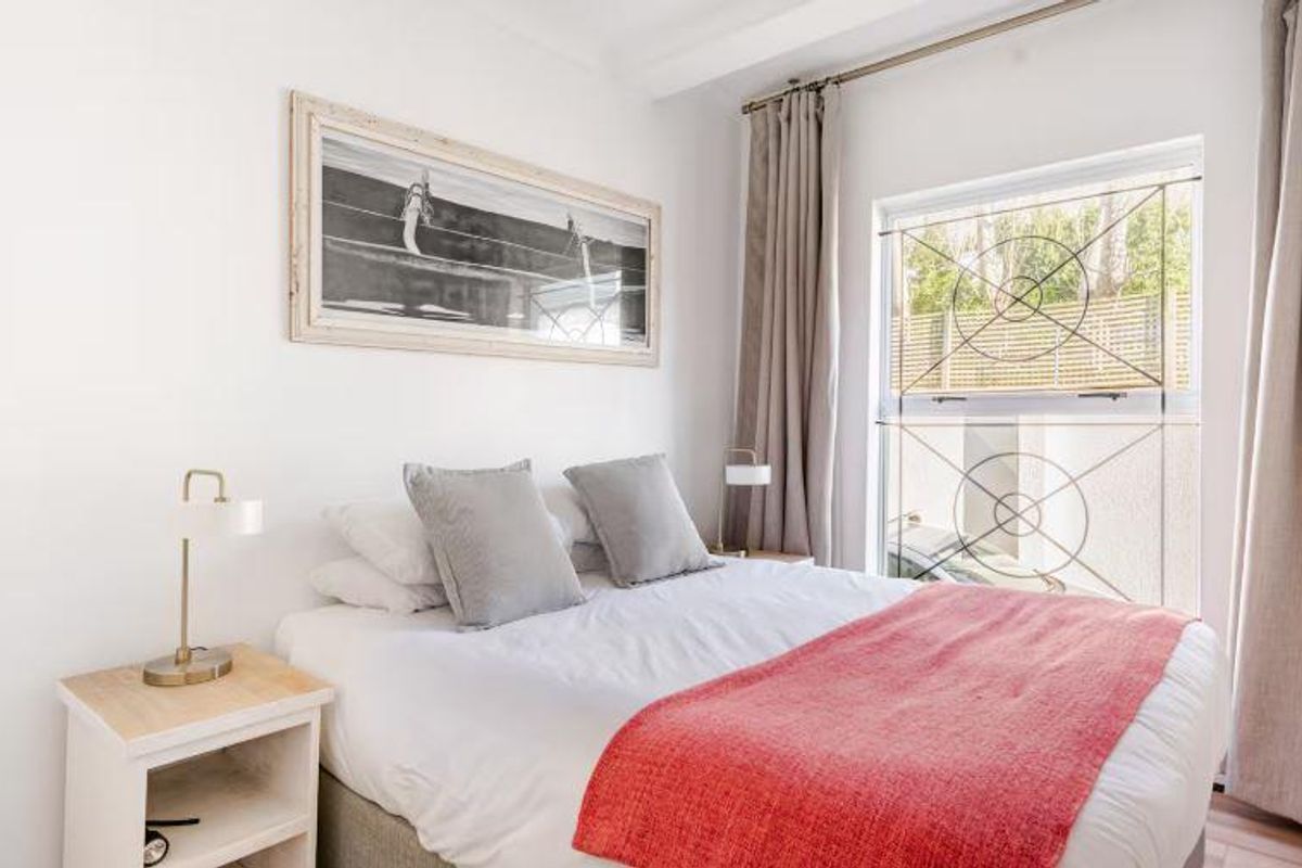 A bright and well-maintained bedroom featuring a large window with decorative security bars and neutral curtains.