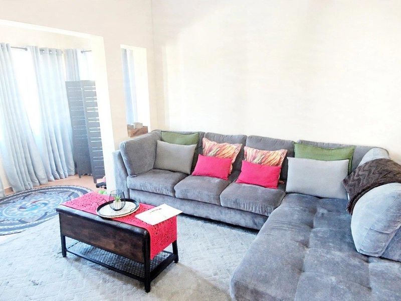 A bright living room featuring tiled flooring and large sliding glass doors that provide ample natural light to the space.
