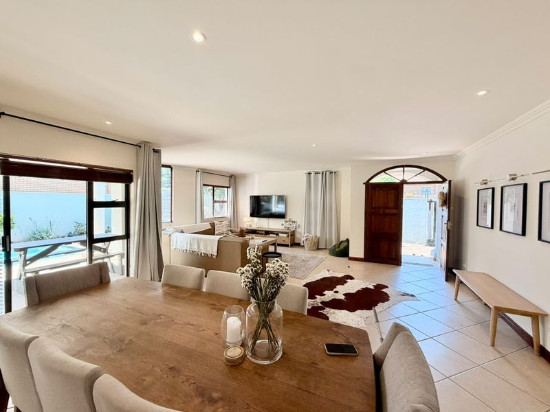 Spacious open-plan living and dining area featuring tiled floors, recessed lighting, and direct access to the outdoor patio and pool area.