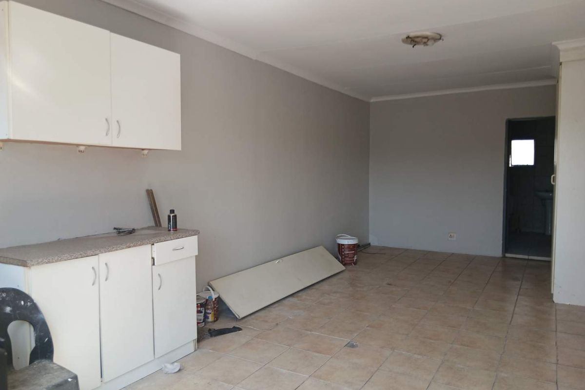 An empty kitchen area featuring basic white cabinetry, laminate countertops, and tiled flooring, currently undergoing minor maintenance or renovation.