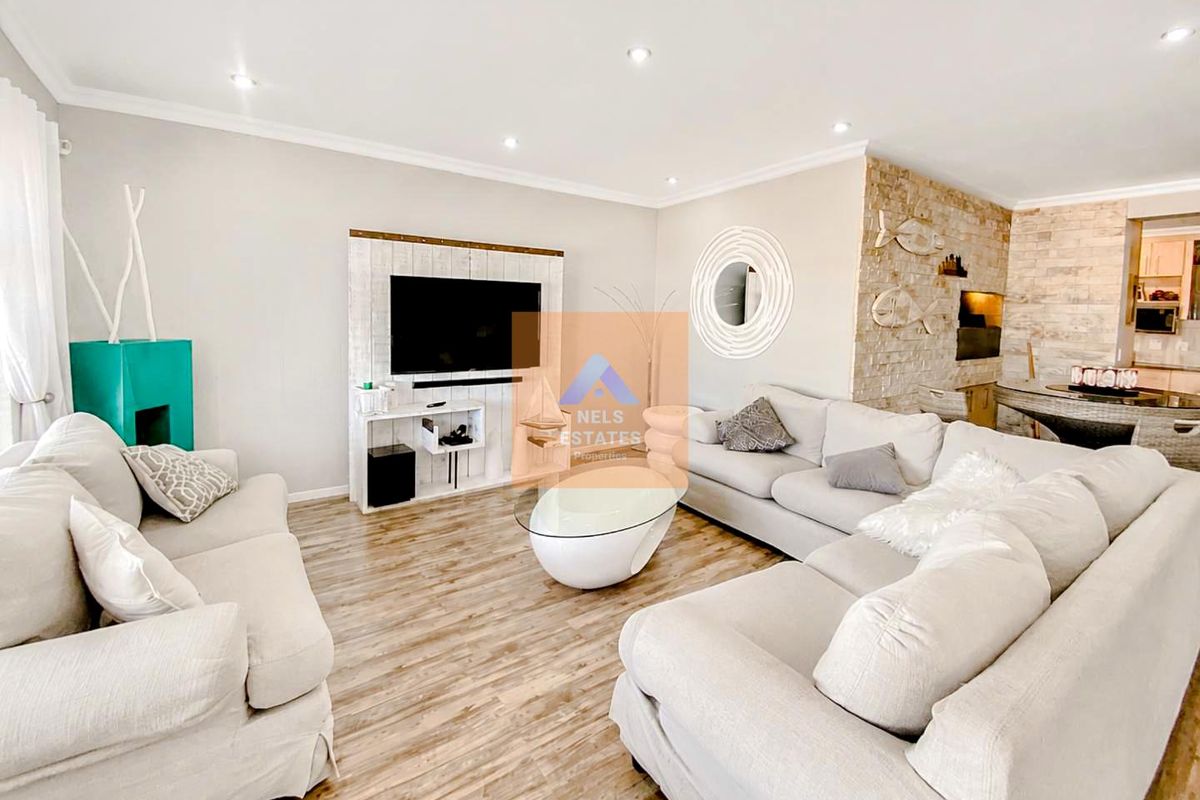 Spacious living room featuring a stone accent wall, recessed downlighting, and modern laminate flooring, creating a bright and inviting atmosphere.