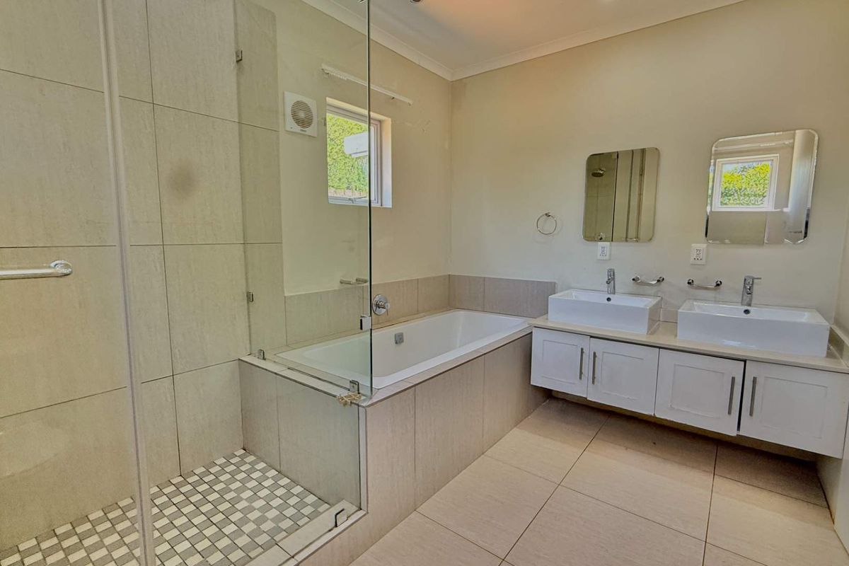 A clean, modern bathroom featuring a glass-enclosed shower, a built-in bathtub, and a double vanity with contemporary sinks.