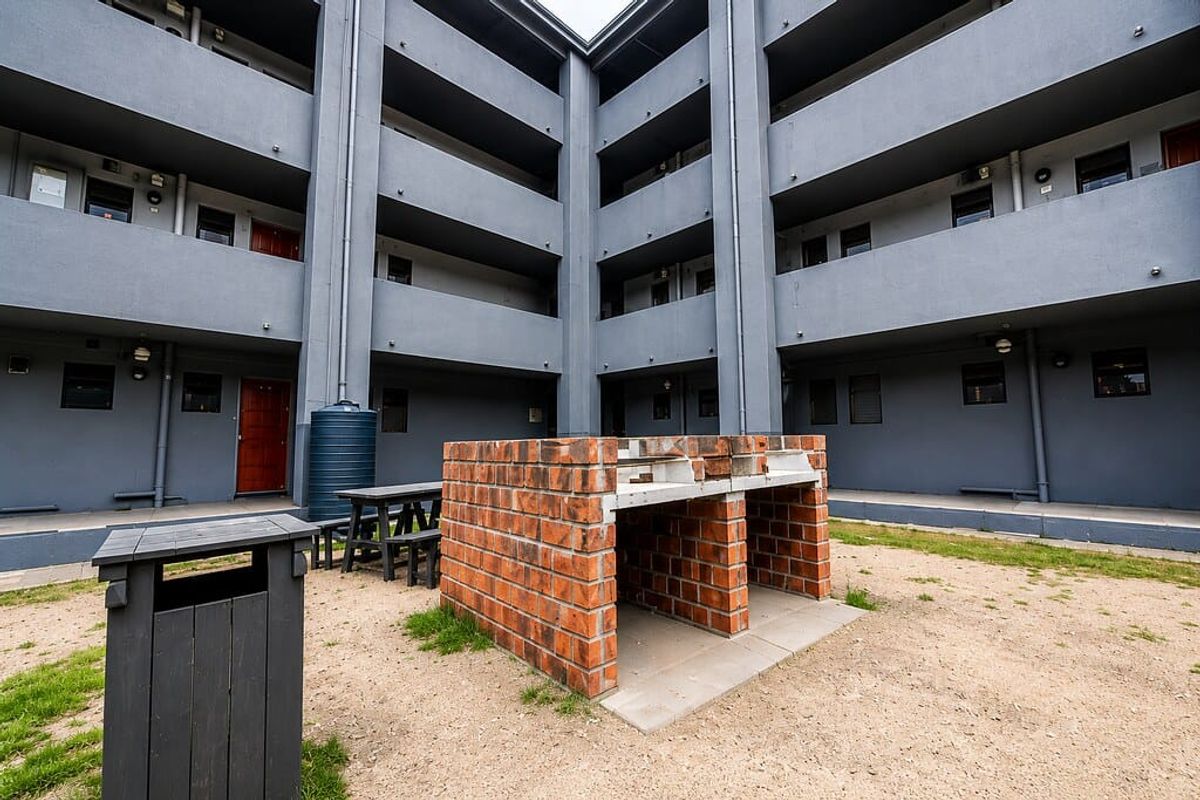 Communal courtyard area featuring a built-in brick braai facility and water tank, set within a multi-story apartment complex.