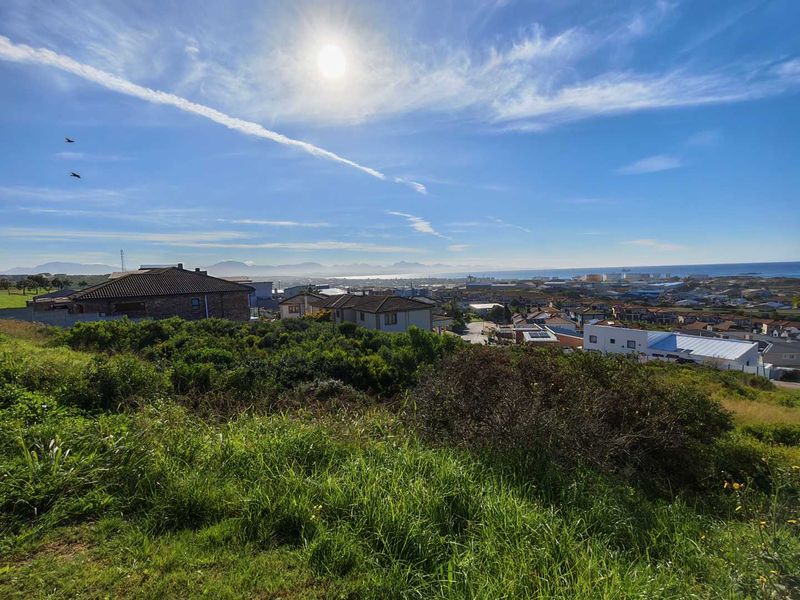 A scenic elevated view overlooking the surrounding residential neighborhood, coastal area, and distant mountain range under a bright sunny sky.