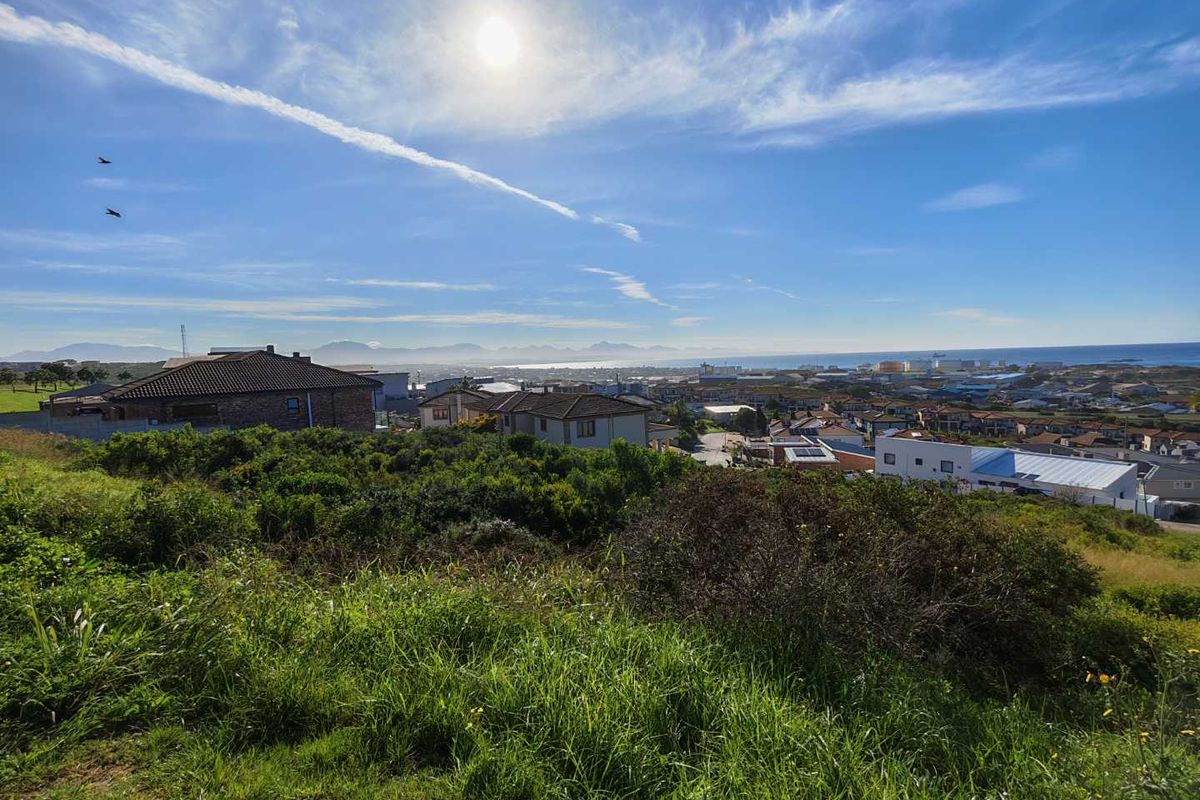 A scenic elevated view overlooking the surrounding residential neighborhood, coastal area, and distant mountain range under a bright sunny sky.