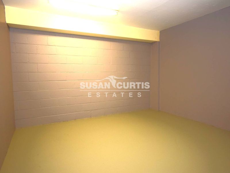 A clean, empty utility space featuring painted concrete block walls and durable concrete flooring, suitable for storage or workshop use.