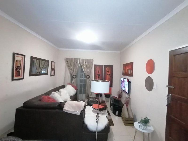 A living room featuring tiled flooring, coved ceilings, and a solid timber entrance door.