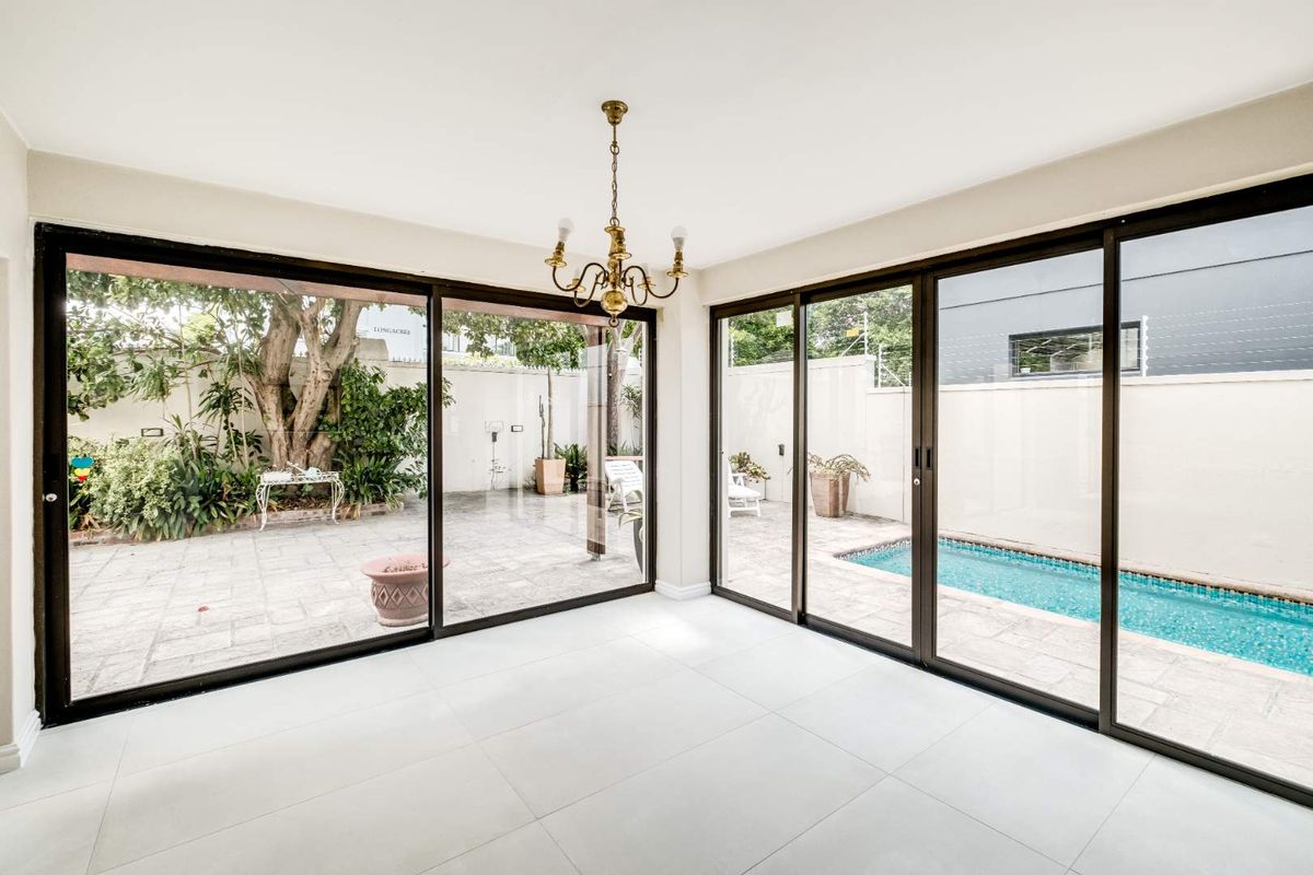 Bright living area featuring large sliding glass doors that open directly onto a paved patio and swimming pool area.