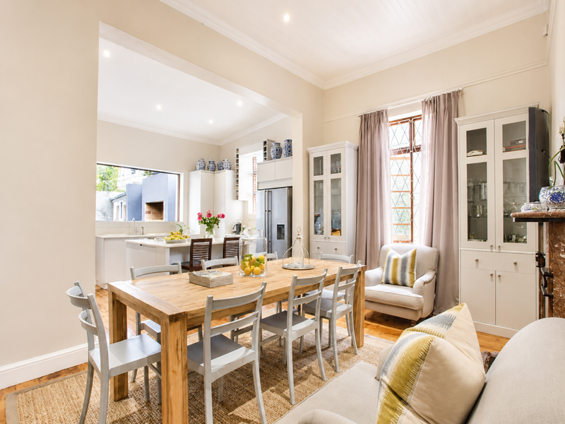 Spacious open-plan living and dining area featuring timber flooring, crown molding, and a modern kitchen with a central island and built-in cabinetry.