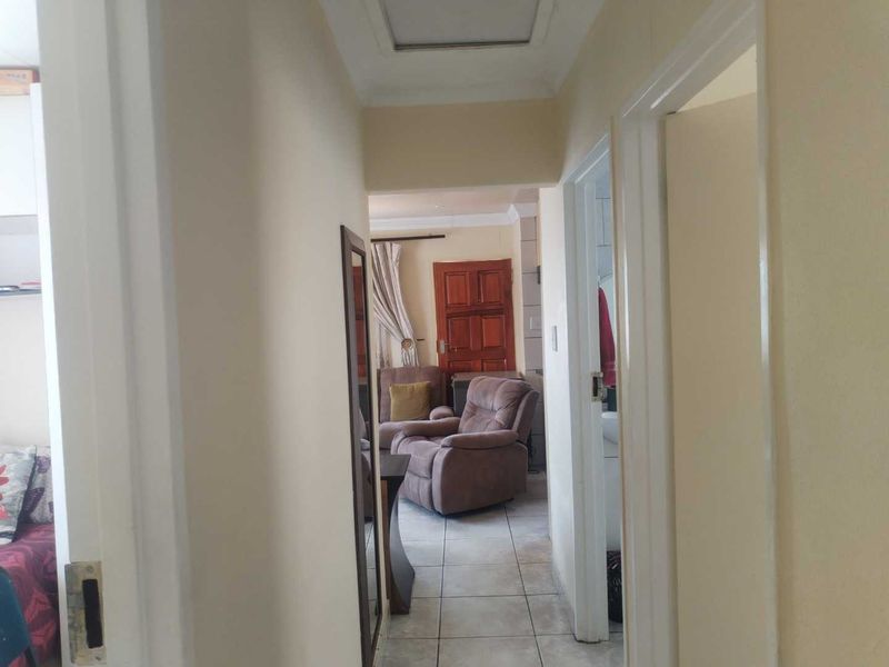A functional interior hallway featuring tiled flooring and a ceiling access hatch, providing access to adjacent rooms within the home.