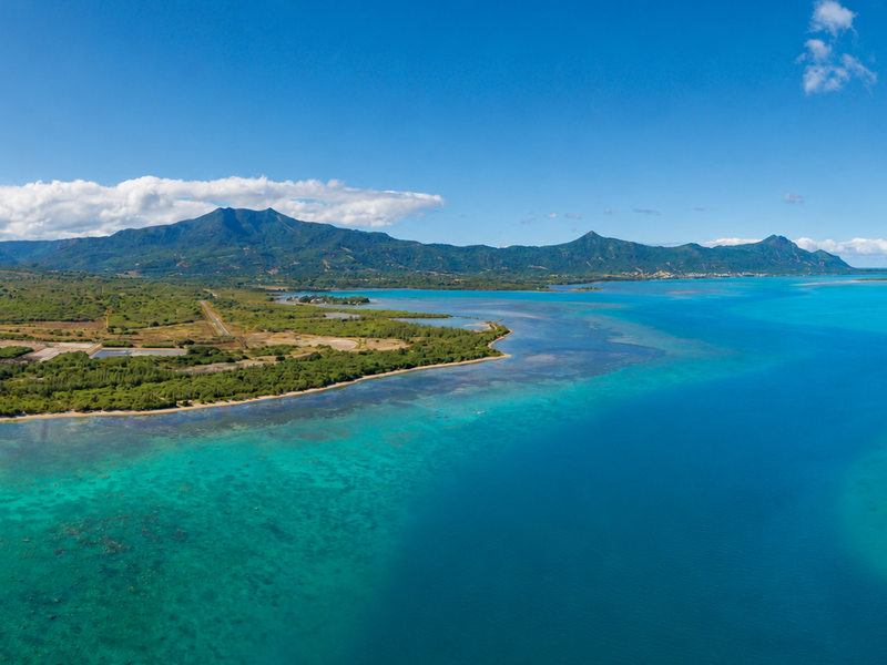 Panoramic aerial view of the coastline, turquoise lagoon, and surrounding mountain landscape.