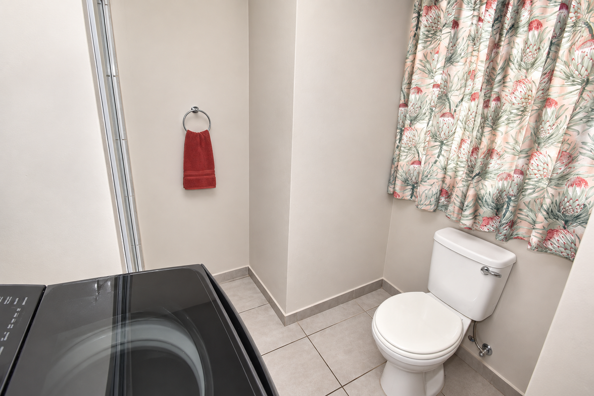 A functional bathroom featuring a standard toilet, tiled flooring, and a wall-mounted towel ring, providing essential utility within the apartment.