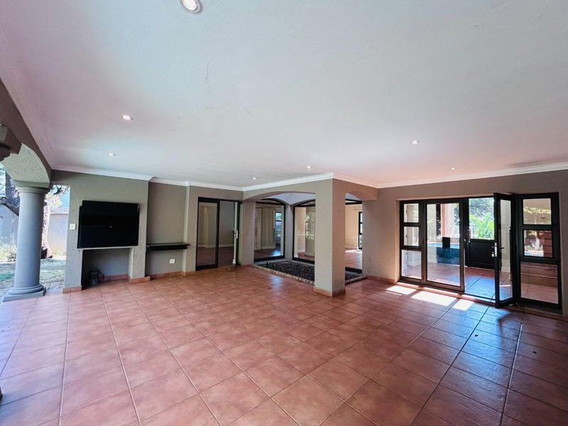 Spacious covered patio featuring tiled flooring, built-in fireplace, and multiple glass sliding doors leading to the garden and pool area.