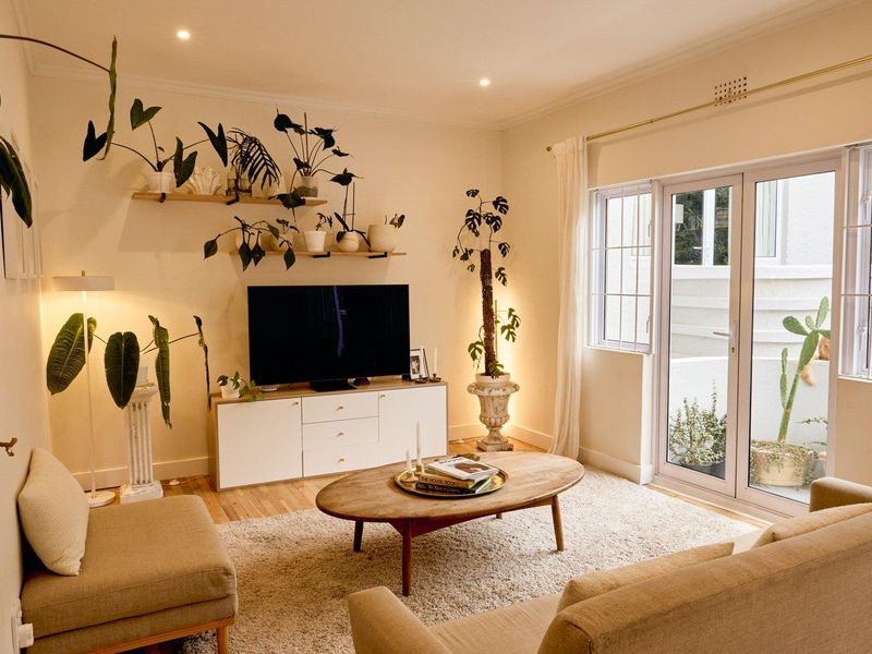A bright and inviting living room featuring hardwood flooring, recessed lighting, and glass french doors that open to an outdoor area.