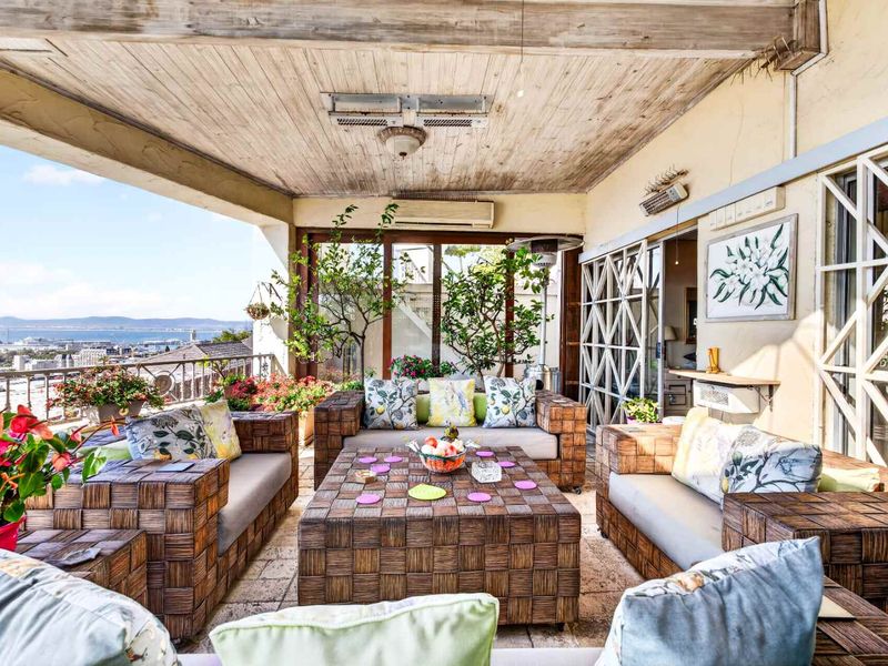Spacious covered balcony featuring stone flooring, exposed timber ceiling, and expansive views, providing an ideal outdoor entertainment area.