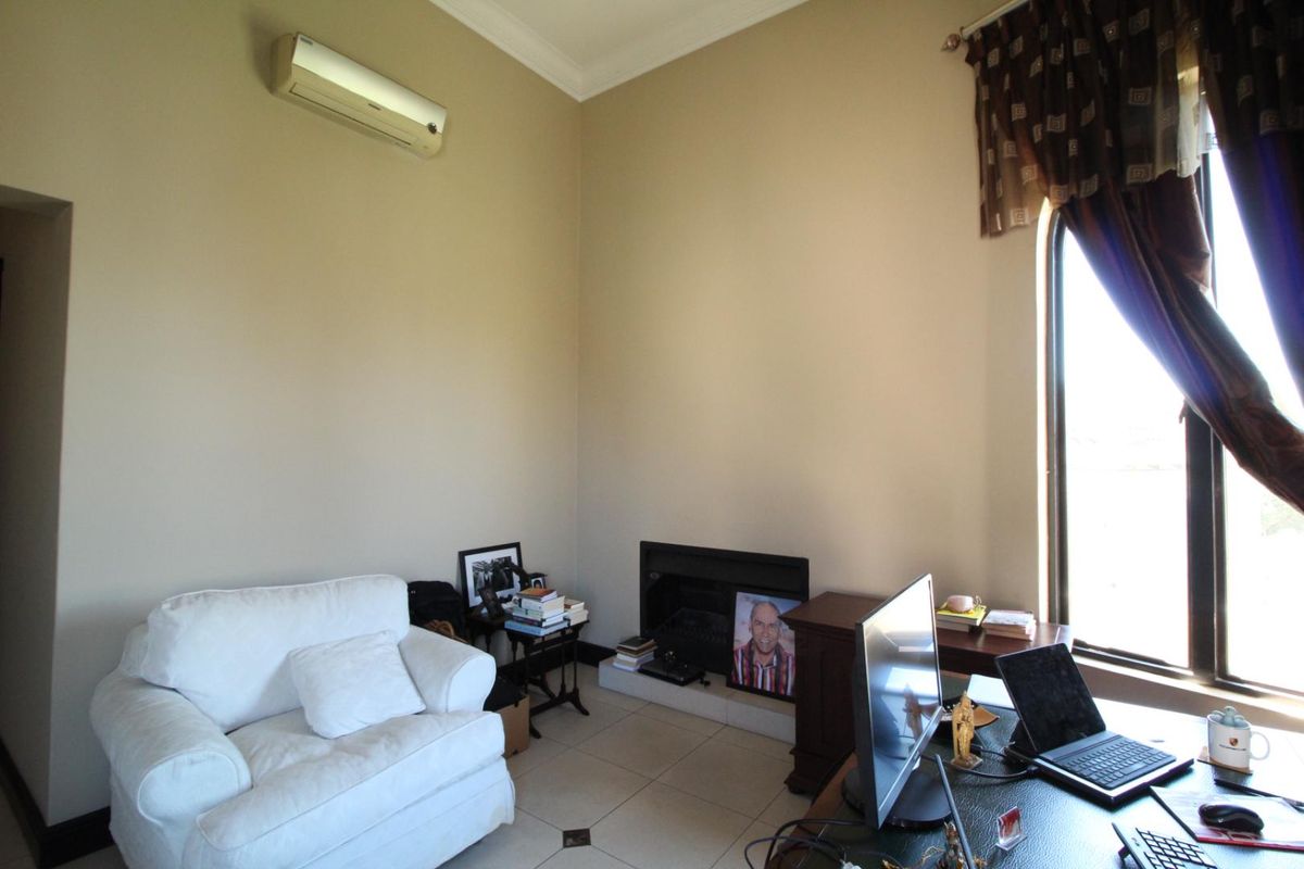A living area featuring a built-in fireplace, tiled flooring, and a wall-mounted air conditioning unit.