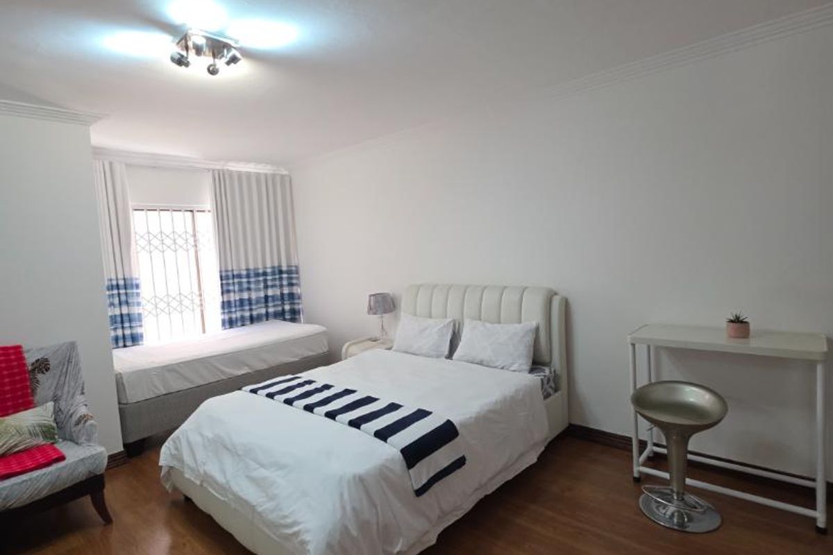 A well-maintained bedroom featuring laminate flooring, neutral walls, and a security gate on the window.