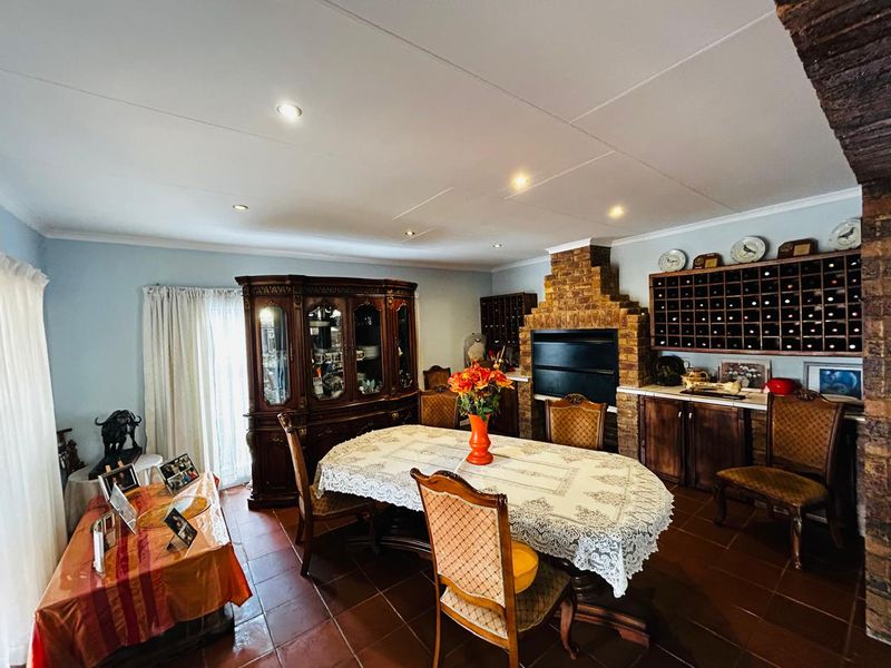Spacious dining room featuring a rustic brick fireplace, built-in wine storage, terracotta floor tiles, and recessed lighting.