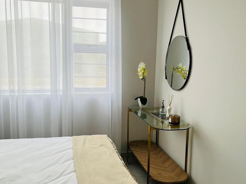 A bright and well-maintained bedroom featuring tiled flooring, a tongue and groove ceiling, and large windows allowing for natural light.