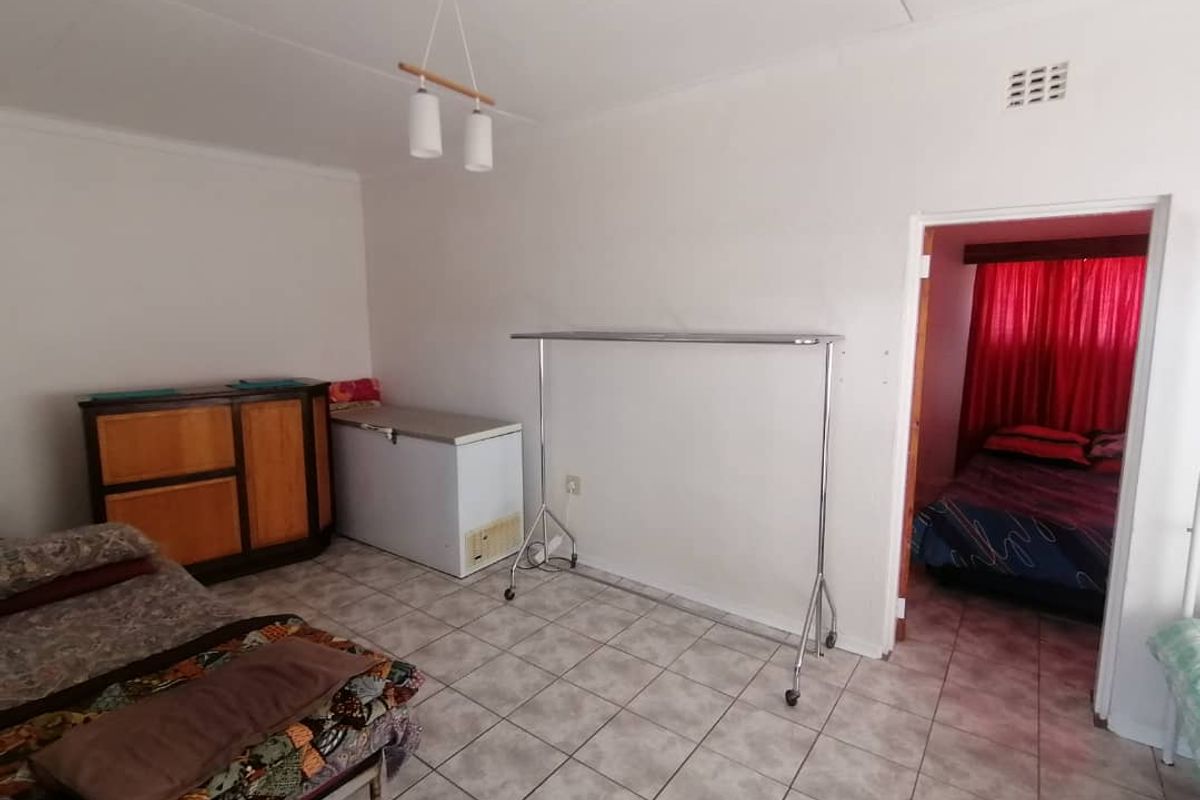 A functional living space featuring tiled flooring and a doorway leading to an adjacent bedroom.