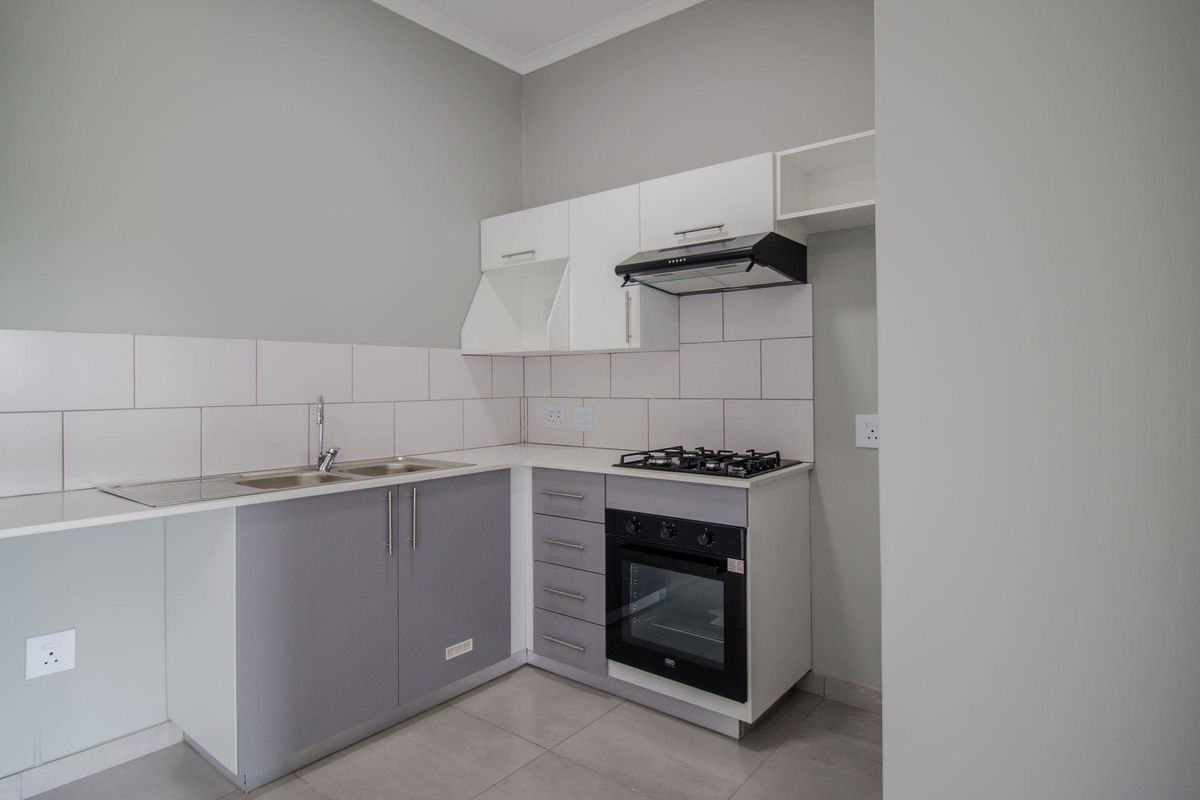 Modern kitchen featuring grey and white cabinetry, tiled backsplash, built-in oven, gas hob, and extractor fan.