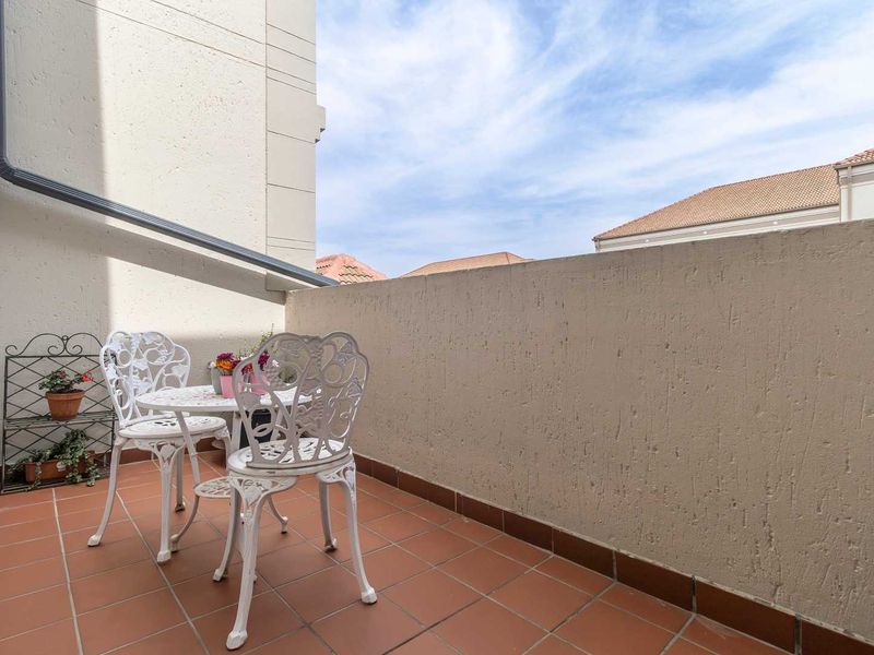 A private balcony featuring tiled flooring and a solid parapet wall, offering an open-air space for outdoor relaxation.