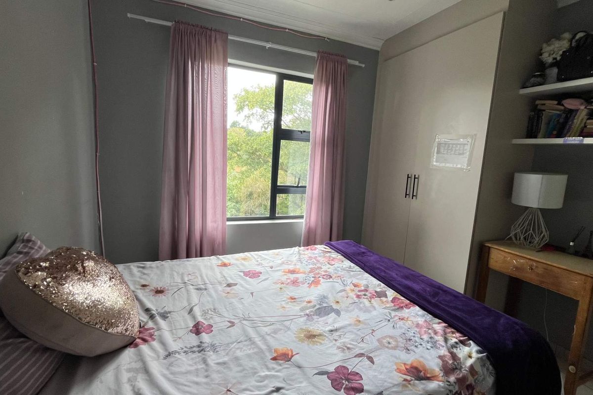 A bedroom featuring built-in cupboards, a window with garden views, and neutral wall finishes.