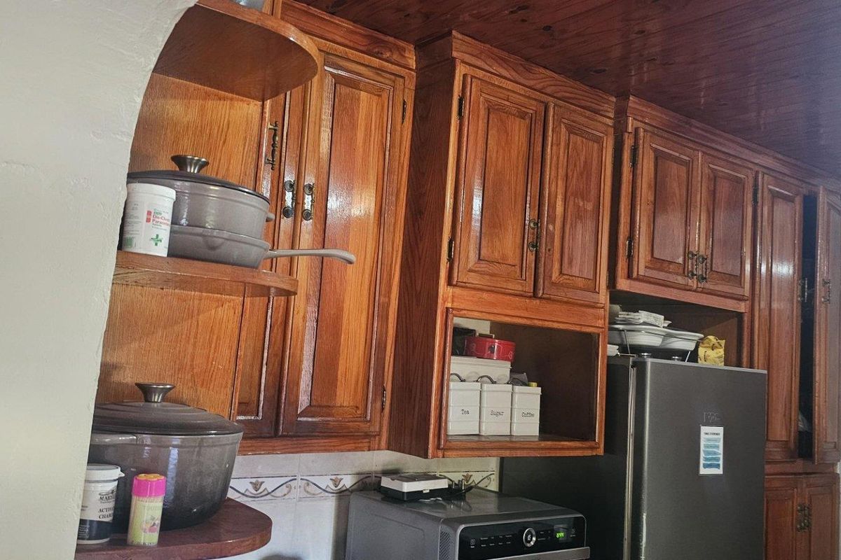 A traditional kitchen featuring extensive timber cabinetry, wood-paneled ceiling, and tiled splashbacks, offering a classic aesthetic with functional storage space.