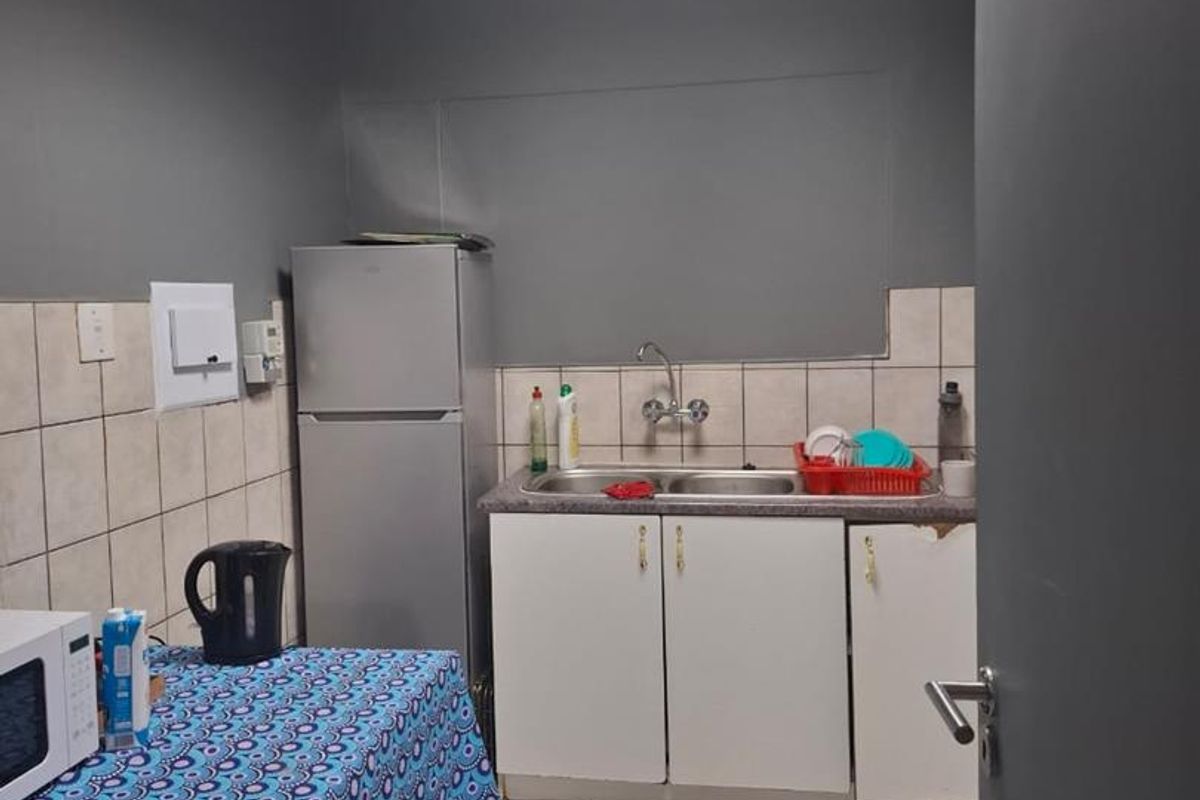 A compact kitchenette featuring a stainless steel sink, built-in base cabinetry, and tiled splashbacks, suitable for a small office or utility space.