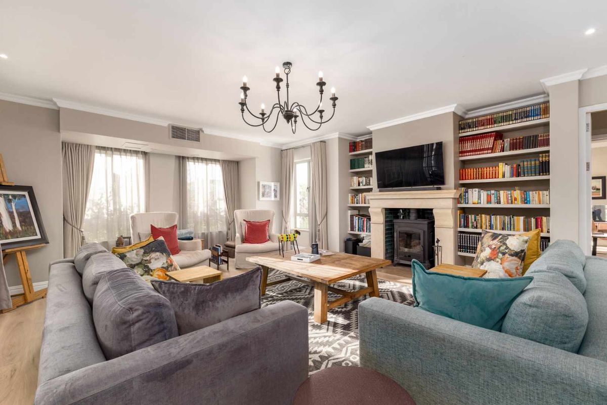 Spacious living room featuring a stone fireplace with a wood-burning stove, extensive built-in bookshelves, and elegant crown molding.
