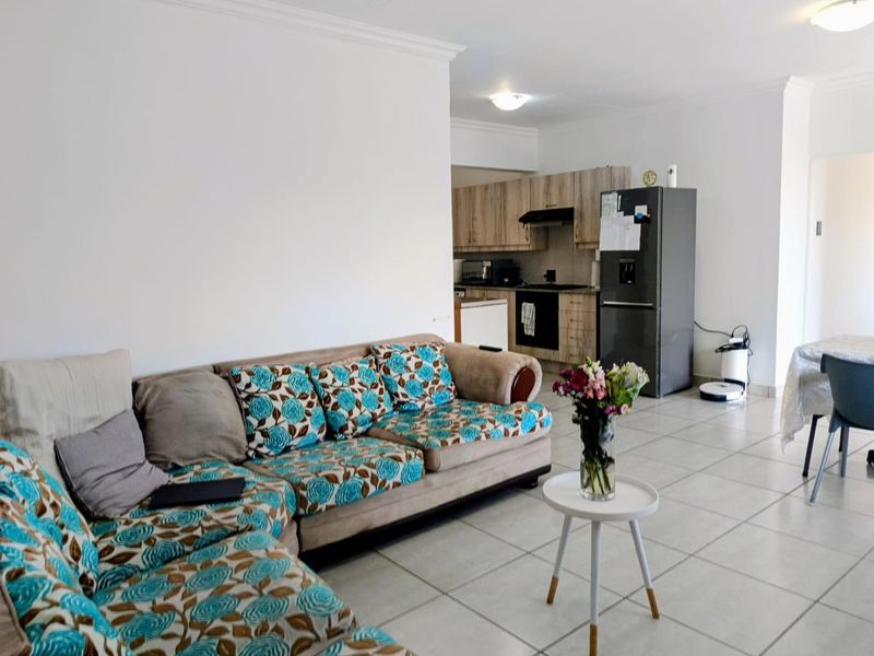 Open-plan living area featuring tiled flooring and a functional kitchen with built-in cabinetry, oven, and extractor fan.