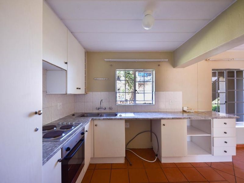A functional kitchen featuring built-in cabinetry, laminate countertops, an electric stove and oven, and tiled flooring, offering a blank canvas for renovation.