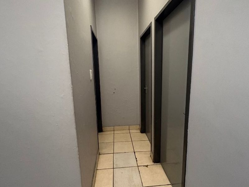 A narrow interior hallway featuring tiled flooring and multiple internal doors, providing access to various rooms within the apartment.