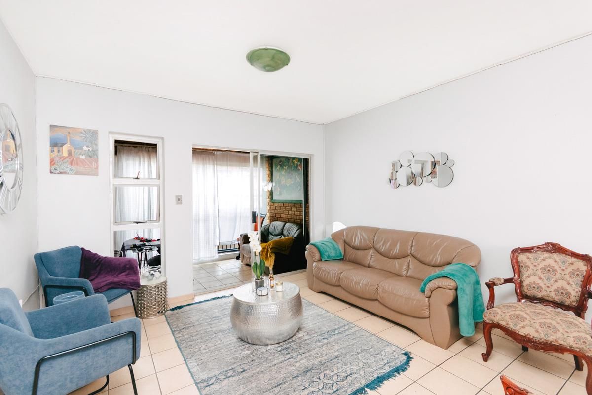 A living room featuring tiled flooring and sliding glass doors that provide access to an adjoining patio area.