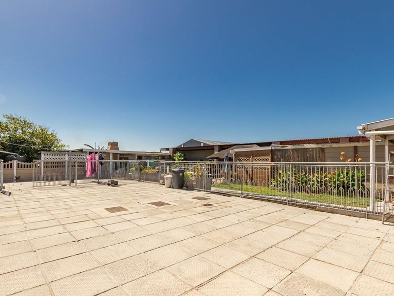 A spacious, paved outdoor patio area enclosed by metal fencing, offering a functional space for outdoor activities.