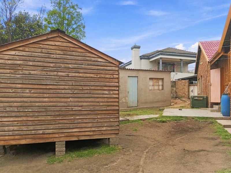 Rear yard area featuring a timber-clad structure, a secondary masonry outbuilding, and views of the main house exterior.