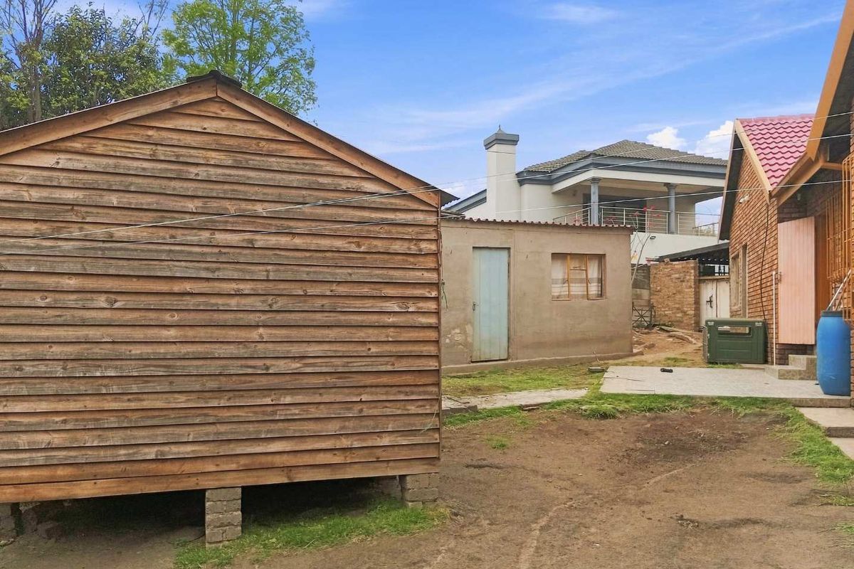 Rear yard area featuring a timber-clad structure, a secondary masonry outbuilding, and views of the main house exterior.