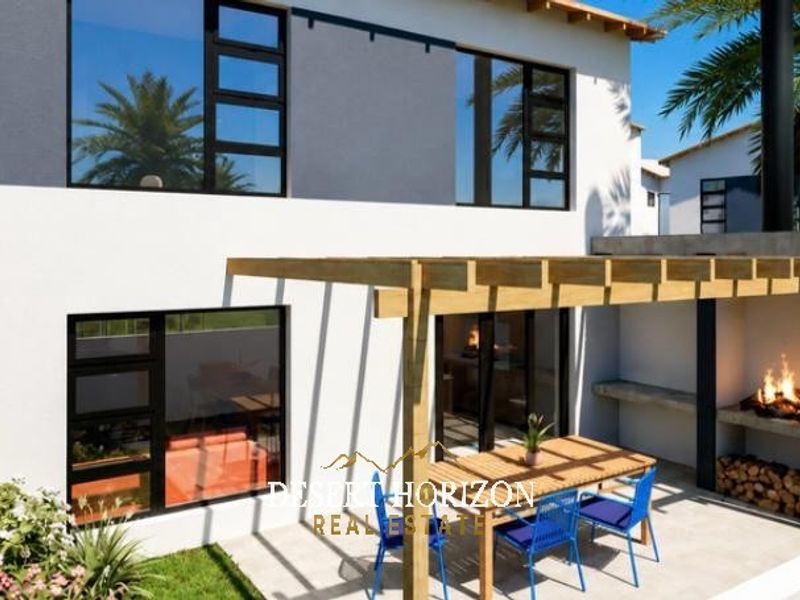Rear exterior view of the townhouse featuring a paved patio with a timber pergola and a built-in braai area.