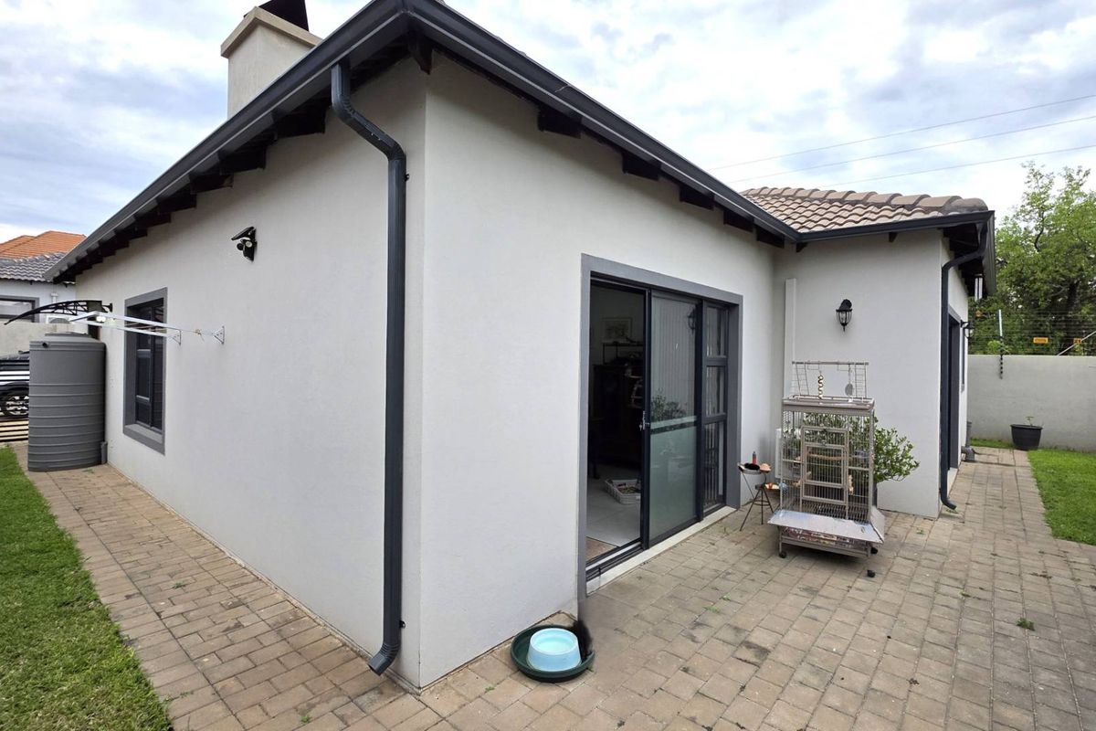 Rear exterior view of the house featuring a paved patio area, sliding glass door access, and a rainwater collection tank.