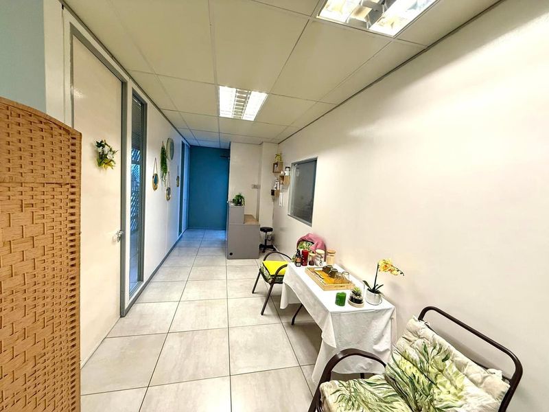 A functional office hallway featuring tiled flooring, recessed ceiling lights, and a built-in reception desk area.