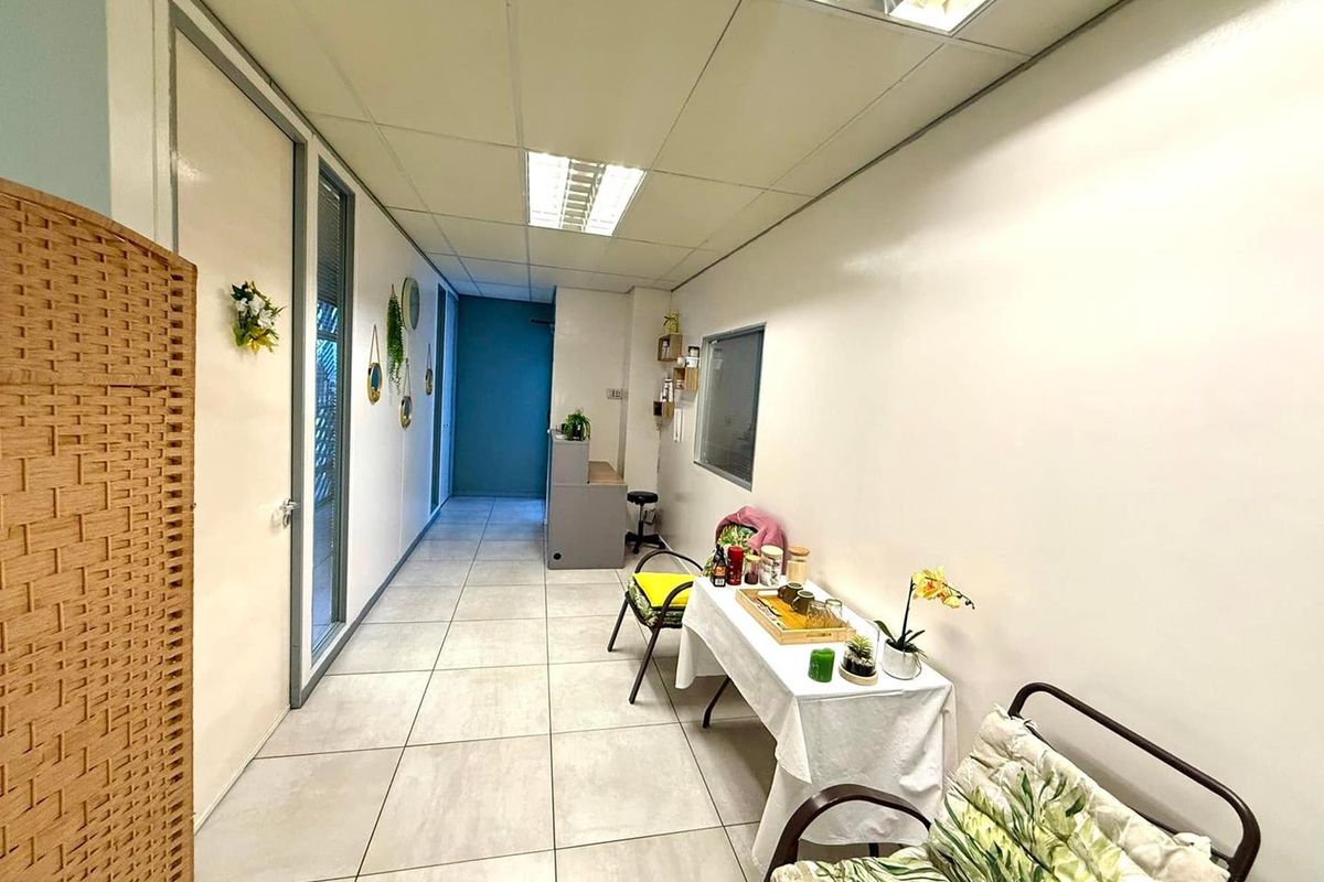 A functional office hallway featuring tiled flooring, recessed ceiling lights, and a built-in reception desk area.