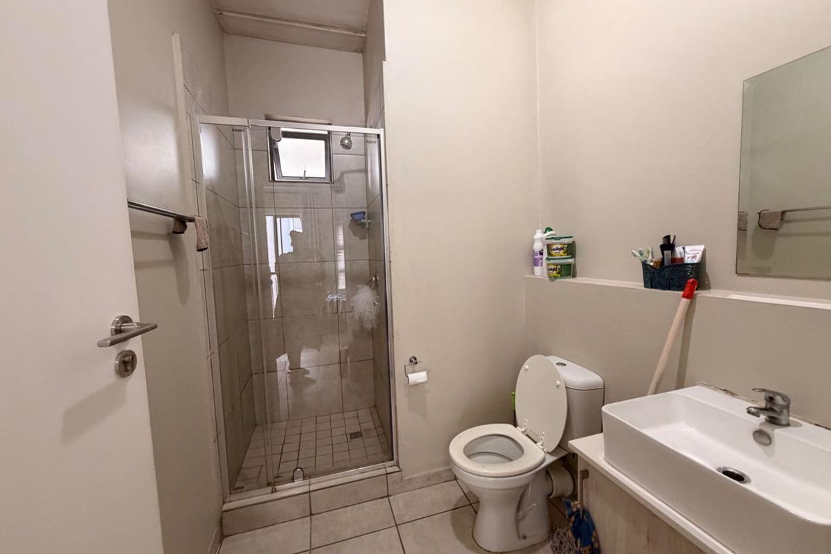A functional bathroom featuring a glass-enclosed shower, a standard toilet, and a modern vessel-style vanity basin with a wall-mounted mirror.