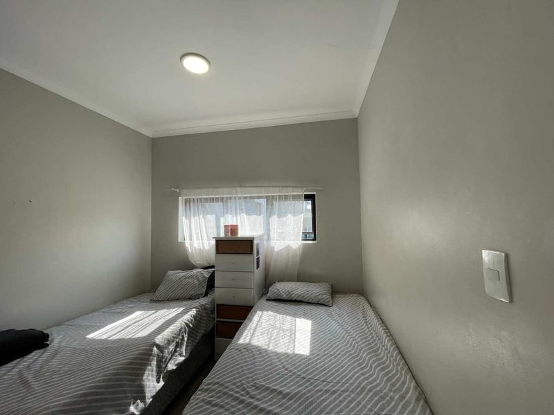 A compact bedroom featuring neutral wall tones, a horizontal sliding window, and cove cornicing, providing a functional space for rest.